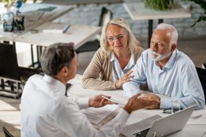 Senior couple talking to real estate agent on a meeting in the office.