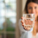 Beautiful young woman smiling while holding a glass of water at
